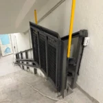 Інвалідний підйомник похилого типу зі складеною вертикальною платформою на сходах усередині будівлі